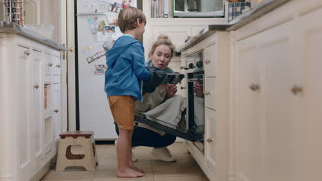 little boy helping mother bake in kitchen taking homemade cupcakes out of oven wearing oven mitts enjoying fresh delicious treats