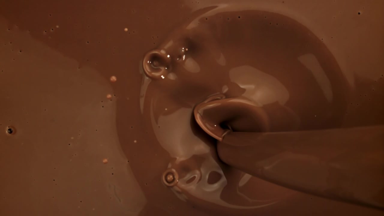 Cioccolato liquido denso che cola e schizza al rallentatore