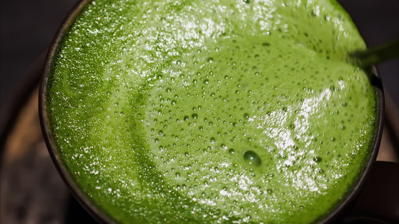 Close up of a spoon mixing into a matcha latte on a tray at a cafe
