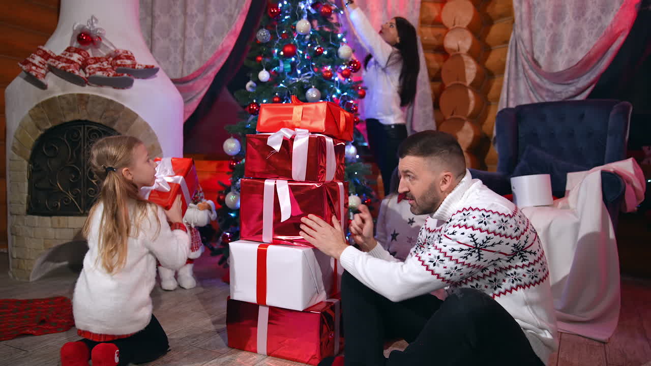 Happy family at Christmas. Father and his daughters near pile of presents in bright boxes. Happy children enjoy with Christmas gifts at home.
