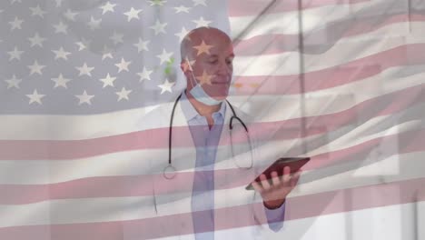 Animation-of-flag-of-america-and-statistics-with-male-doctor-wearing-mask-using-tablet-smiling