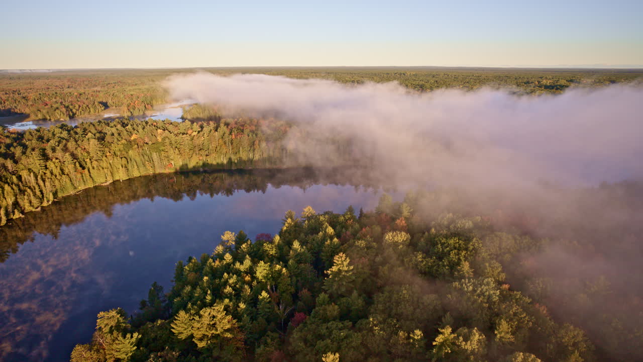 Drone glides overhead, revealing mist rising in warm dawn light