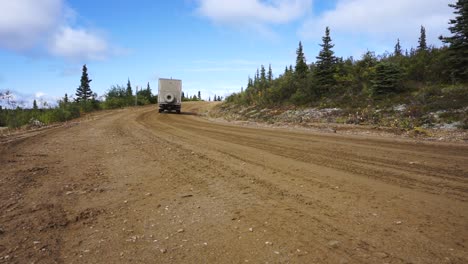 Statischer-Low-Winkel-Schuss-Eines-Großen-Lastwagens,-Der-Eine-Abgelegene-Unbefestigte-Straße-In-Der-Yukon-Region-Von-Alaska,-USA,-Hinunterfährt