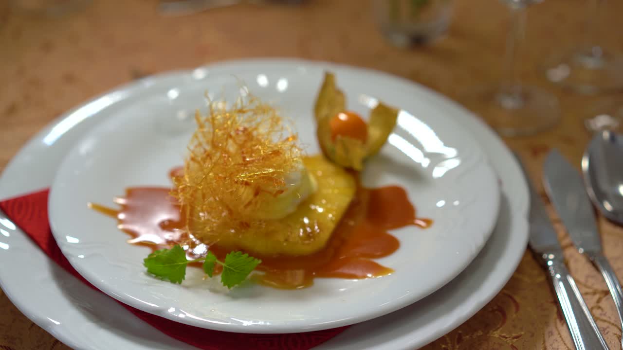 postre dulce con piña, helado de vainilla, caramelo, decoración de azúcar hilado y physalis