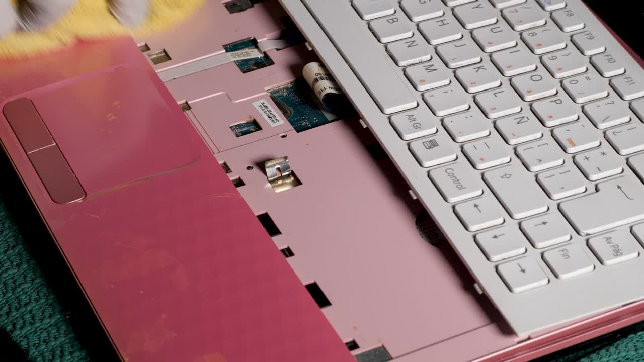 mano de hombres latinos con guantes limpiando su laptop rosa con alcohol y limpiando con un paño de microfibra