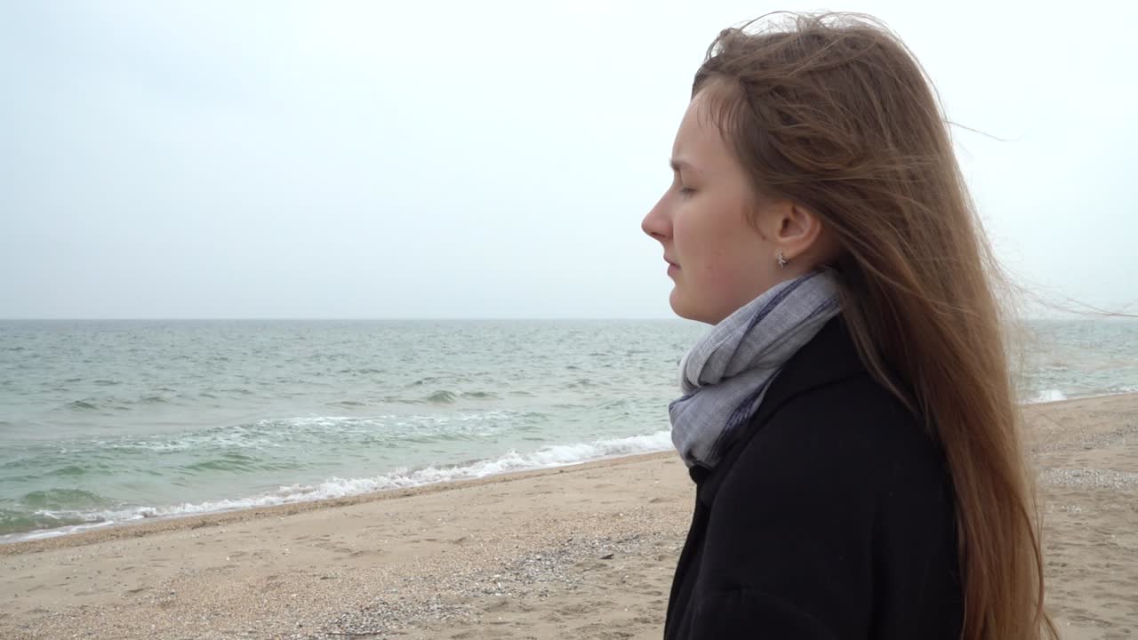 The girl looks at the sea. Slow motion. Shooting on the beach
