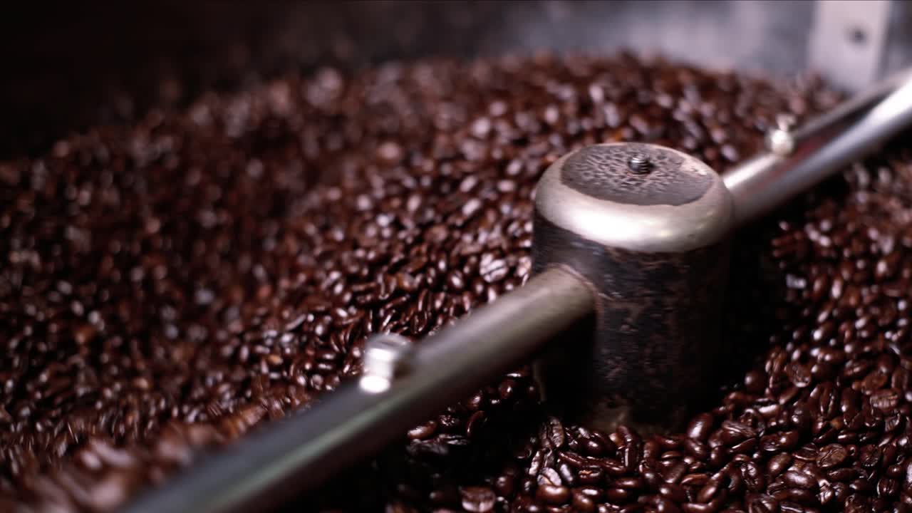 Chicchi di caffè scuri e oleosi, appena usciti dalla tostatrice, vengono mescolati per raffreddare e fermare il processo, al fine di evitare un sapore amaro nella bevanda.
