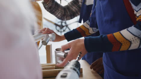 Close-Up-Of-Multi-Cultural-Team-In-Workshop-Assembling-Hand-Built-Sustainable-Bamboo-Bicycle-Frame