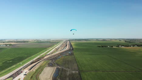 單人 paragliding 飛行在鄉村農業農場的田野風景上空