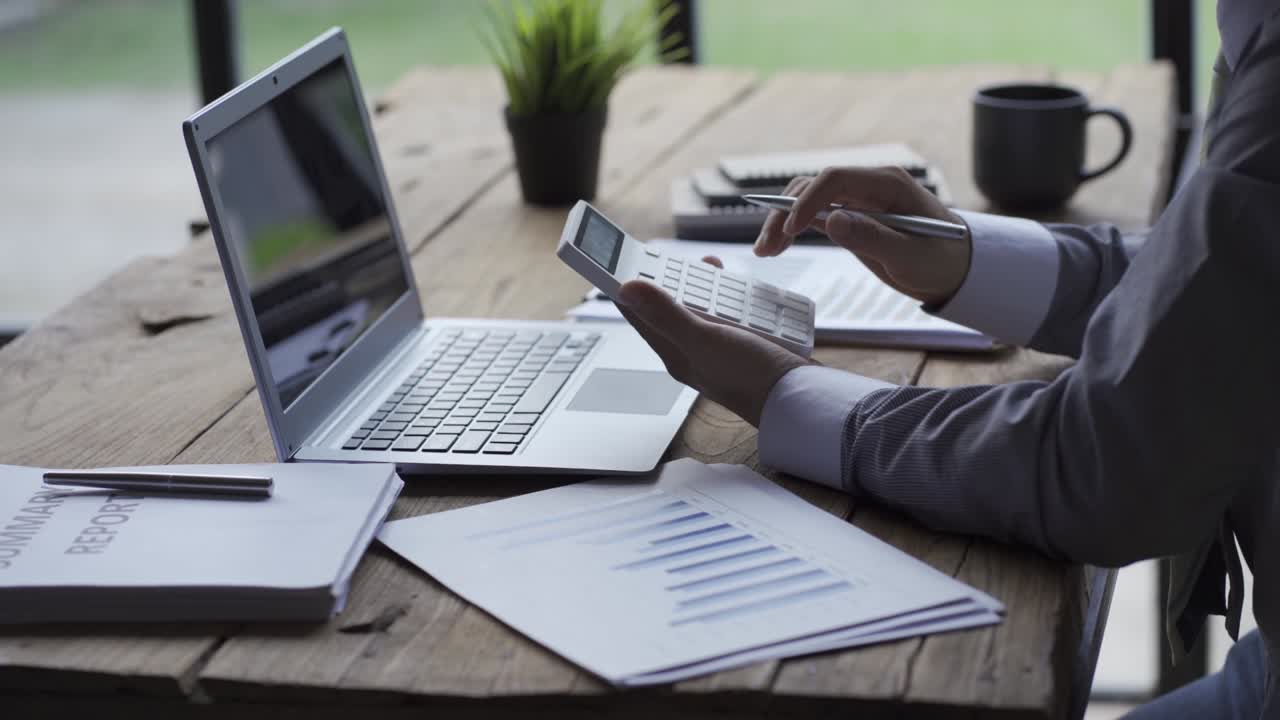 Businessman developing business project and analyzing marketing graph data with accounting documents and financial reports on 4k video table.