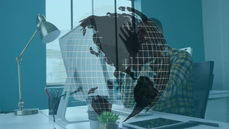 man covering face at office desk, interacting with wireframe globe overlay in technology scenario