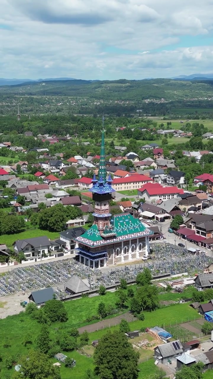 Rekaman drone udara terbang menuju gereja berwarna-warni dan salib kayu yang dicat di Pemakaman Ceria (Cimitirul Vesel) di Sapanta, Rumania