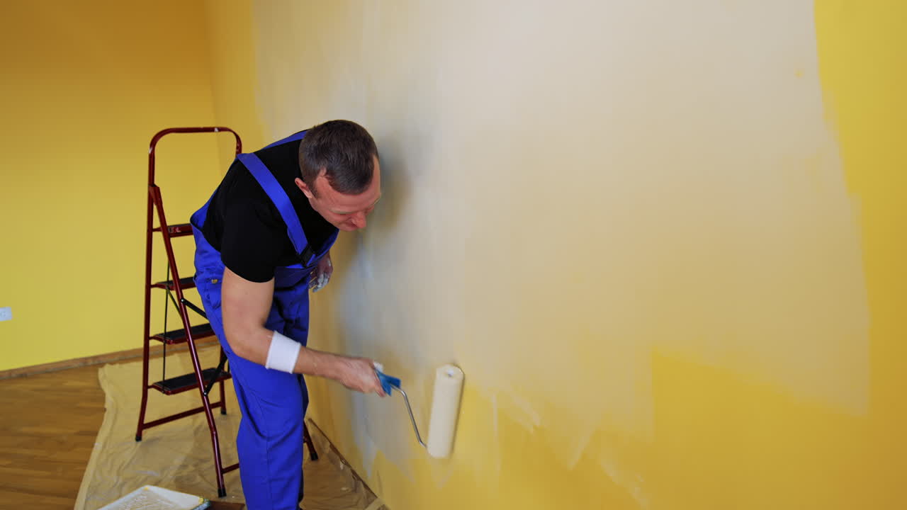 Man painting walls of room. Young male decorator painting wall in the empty room