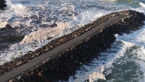aerial view of waves crashing against a rocky jetty at brunswick heads, nsw. dynamic ocean scene with strong lighting and movement