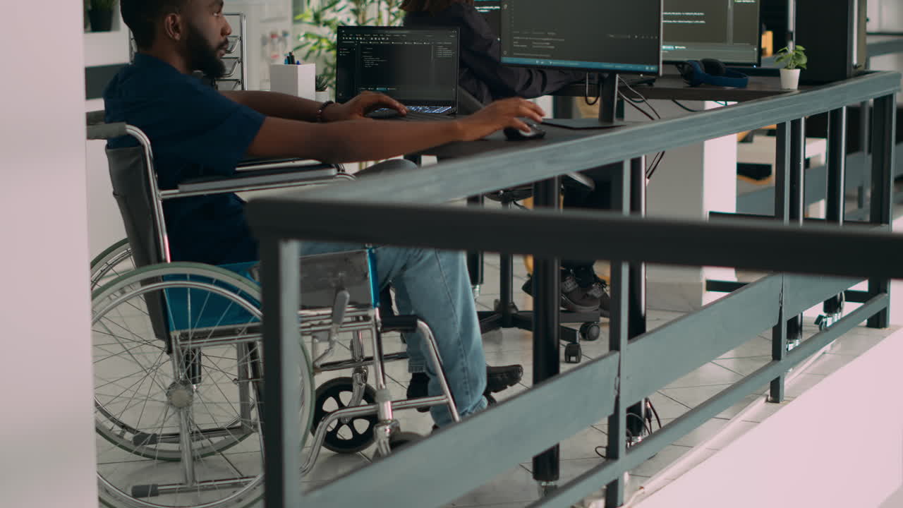 Ingegnere informatico afroamericano con disabilità che digita codice in un'agenzia di sviluppo IT