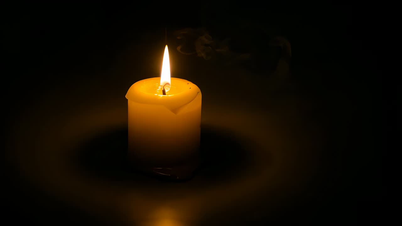 Candela a colonna gialla che si scioglie a causa dello stoppino che brucia, cera che si accumula sul piano riflettente, fiamma che si spegne