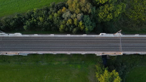 Top-view-of-train-tracks-on-a-bridge-with-surrounding-landscape