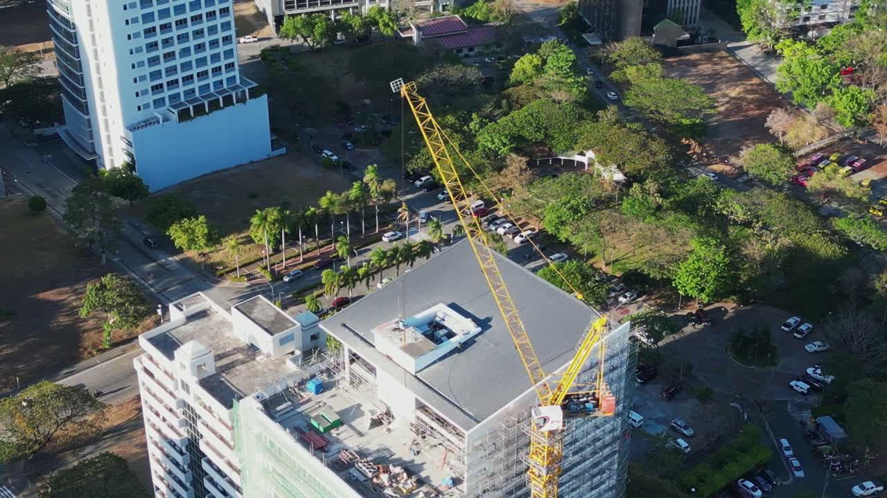 órbita aérea de la parte superior de la grúa y el techo del edificio en construcción en la pintoresca ciudad filipina durante el día