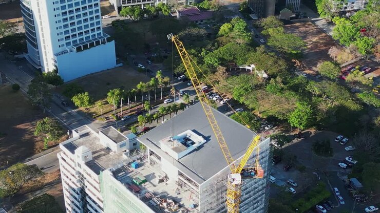 Órbita aérea de la parte superior de una grúa y el tejado de un edificio en construcción en una pintoresca ciudad filipina durante el día
