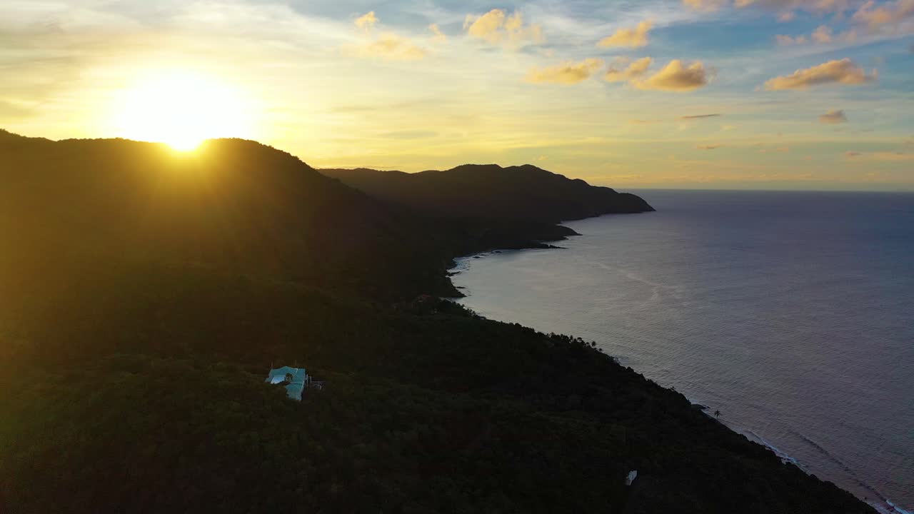 Breathtaking sunset over the Virgin Islands, with the horizon painted in brilliant hues, a forested point stretching into the ocean, and the peaceful rhythm of the waves below