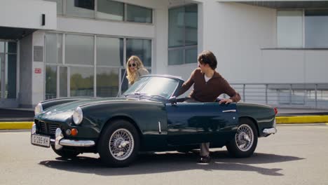 man driving a classic green convertible car