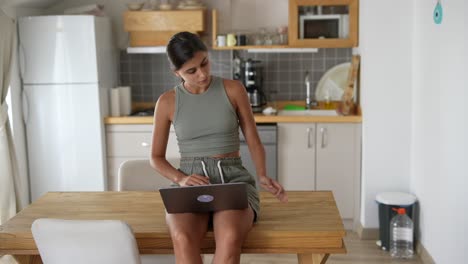 mujer trabajando en una computadora portátil en la cocina