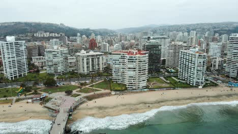 Toma-Aérea-De-Establecimiento-De-La-Ciudad-De-Viña-Del-Mar-Con-Montañas-Y-Cielo-Nublado-Detrás