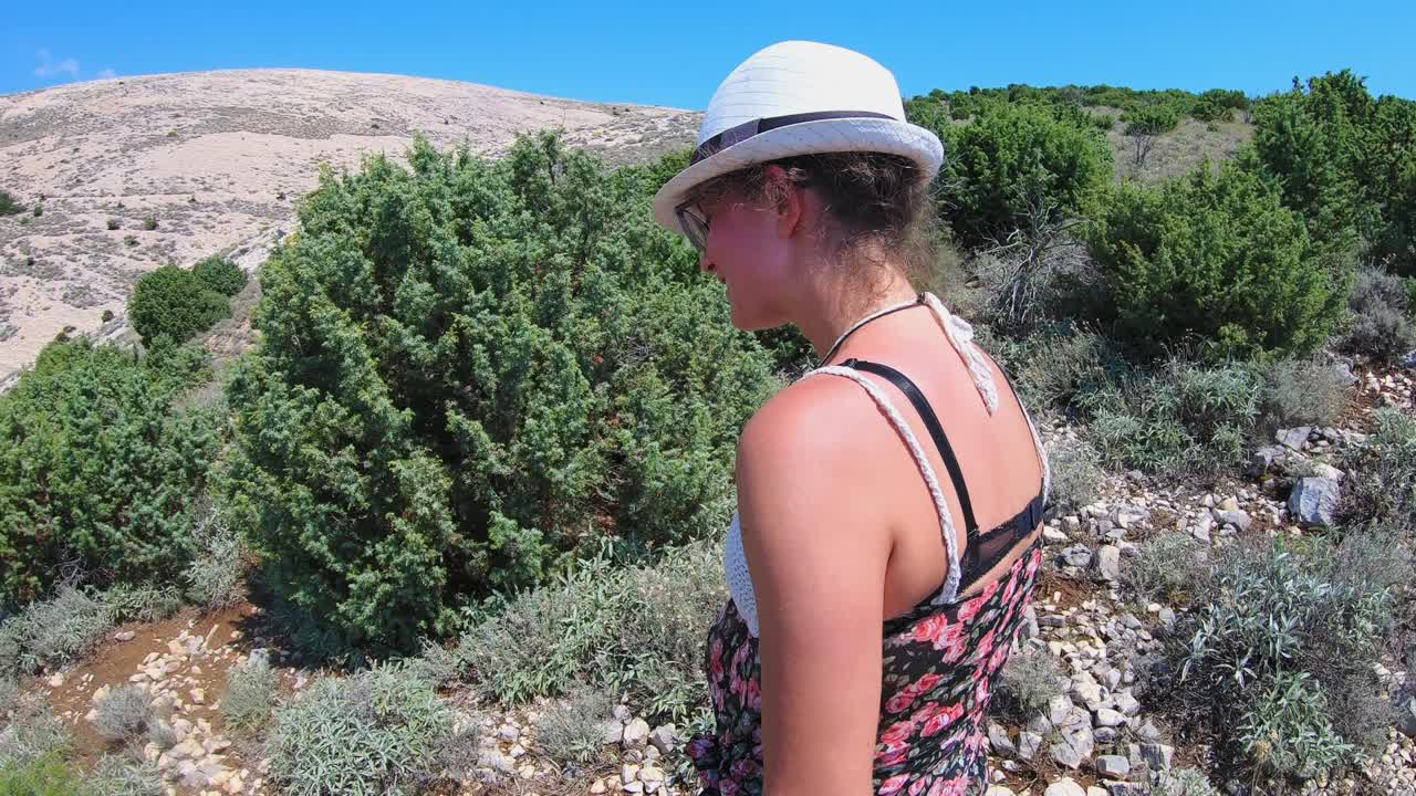 smiling woman walk on the rocky hills of Krk Island. View Adriatic sea. Croatia
