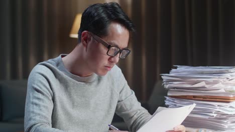 집에서 문서를 작업하는 동안 지표손가락을 올리는 종이를 생각하고 보는 아시아 남자의 클로즈업