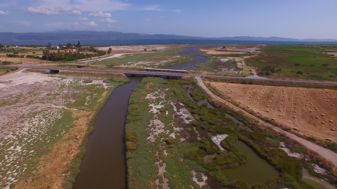 antena: un delta de un río con un puente de carretera que lo atraviesa y algunos edificios agrícolas