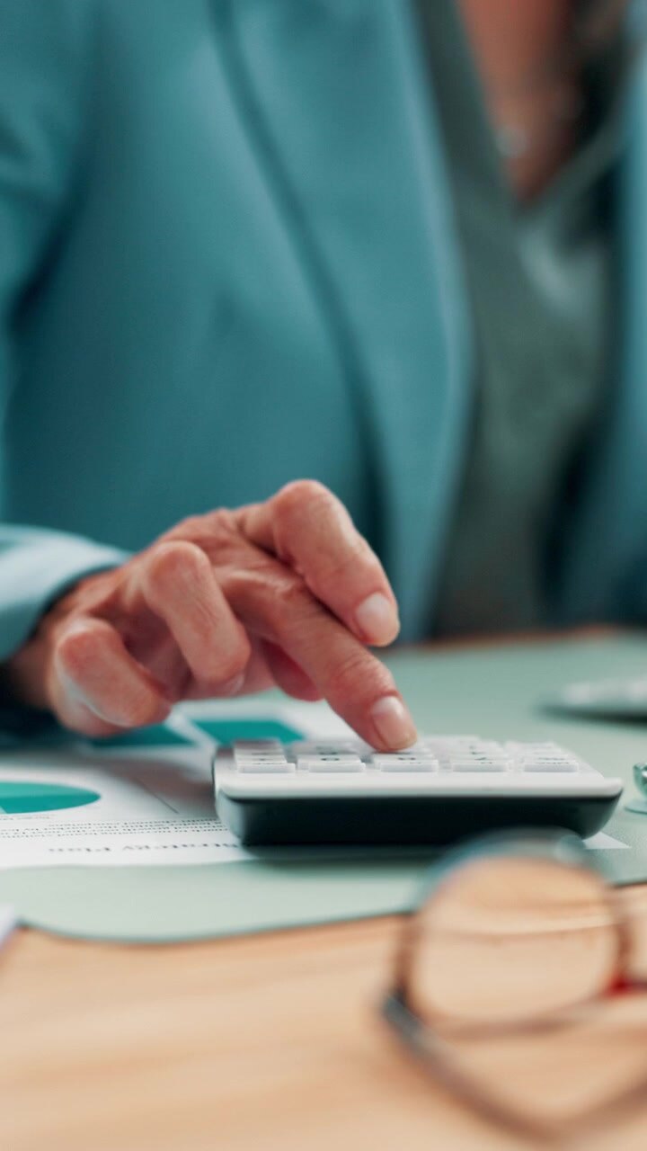 Donna d'affari che usa la calcolatrice per l'analisi finanziaria in ufficio