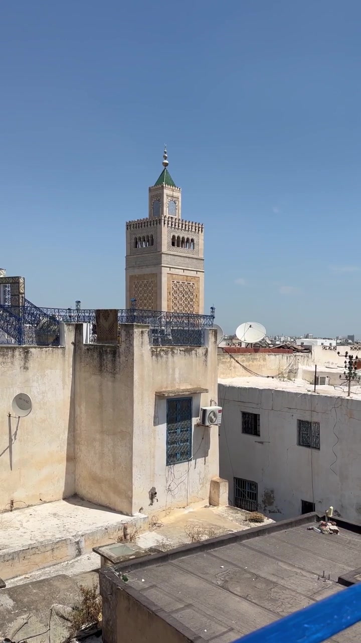 Traditionelle hustage i Tunis' medina og paraboler indrammer en moskéminaret under en klar blå himmel. Tunis, Tunesien.