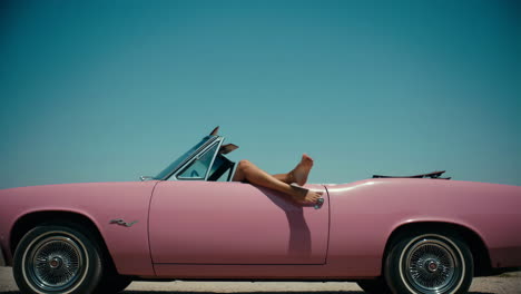 legs out of a pink convertible on a sunny day