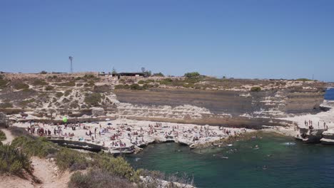 foto panorámica de la piscina de san pedro, la gente disfruta y salta al agua del mar en malta