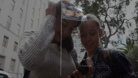 women outdoors using smartphone together, smiling and watching animation content