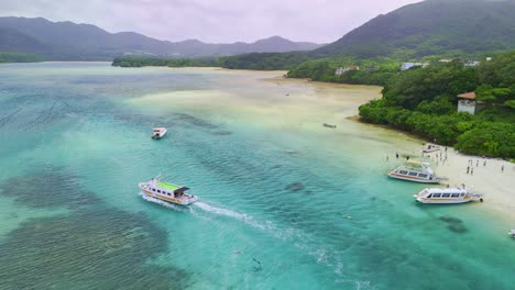 A stunning aerial shot captures a motorboat cruising through the vibrant, clear turquoise waters of a secluded tropical bay surrounded by lush green hills
