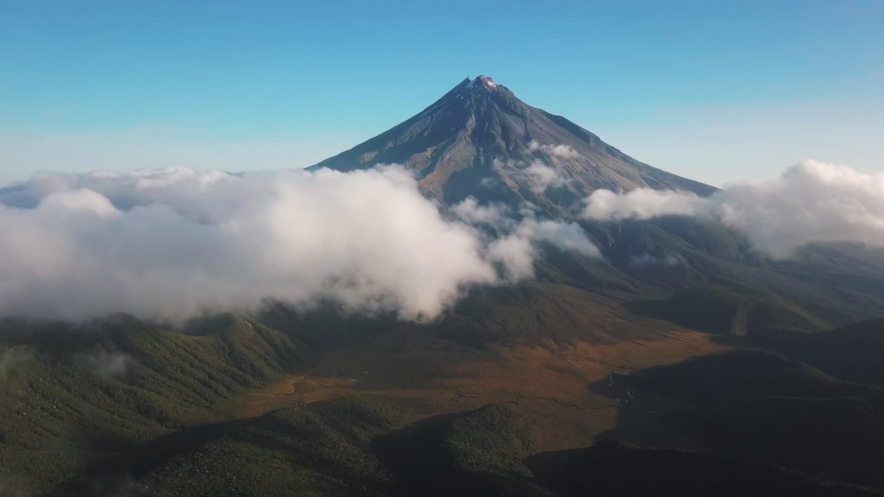toma panorámica del monte taranaki en la distancia detrás de nubes blancas
