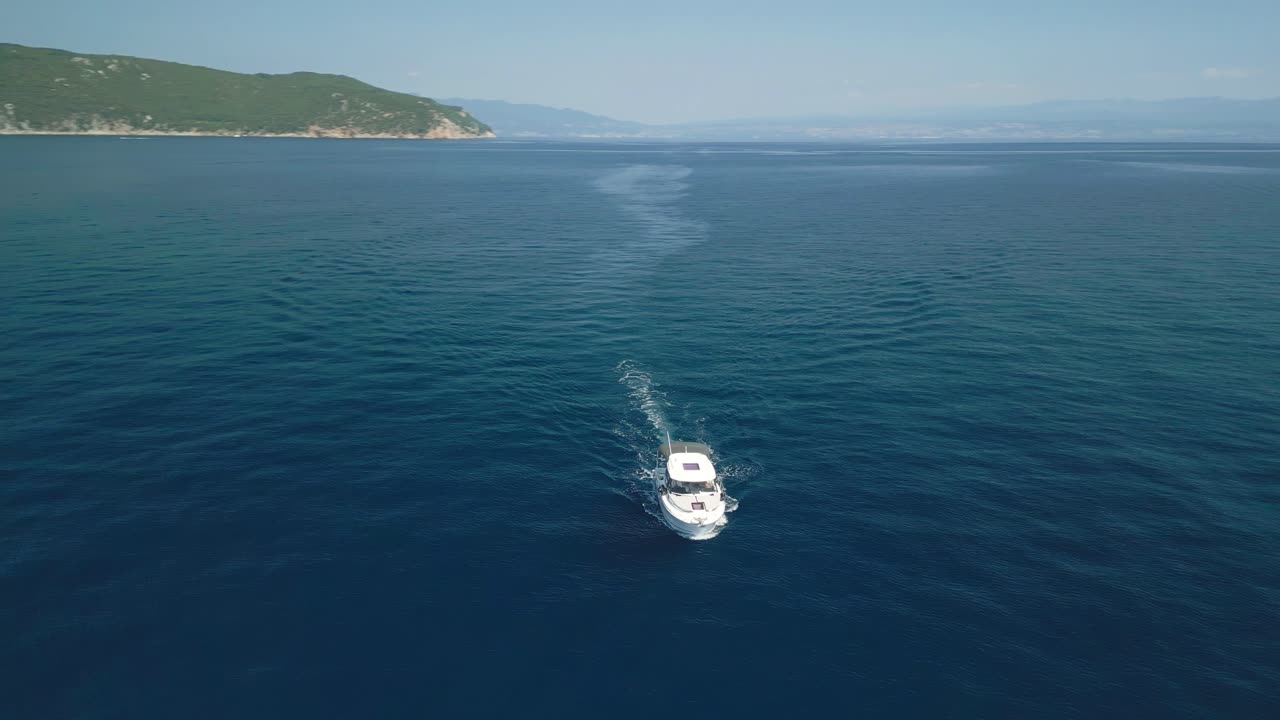 Una barca naviga attraverso il mare calmo e blu con colline verdi sullo sfondo
