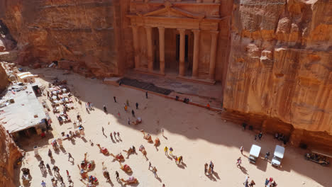 High-angle-tilt-up-from-crowds-to-stone-temple-carved-into-mountain-side