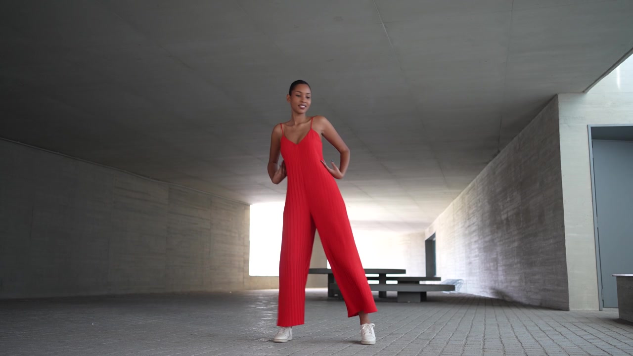 An elegant figure adorned in a stunning red dress within a contemporary architectural space