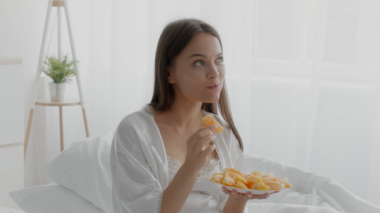 mujer disfrutando de un desayuno de naranja fresca en la cama