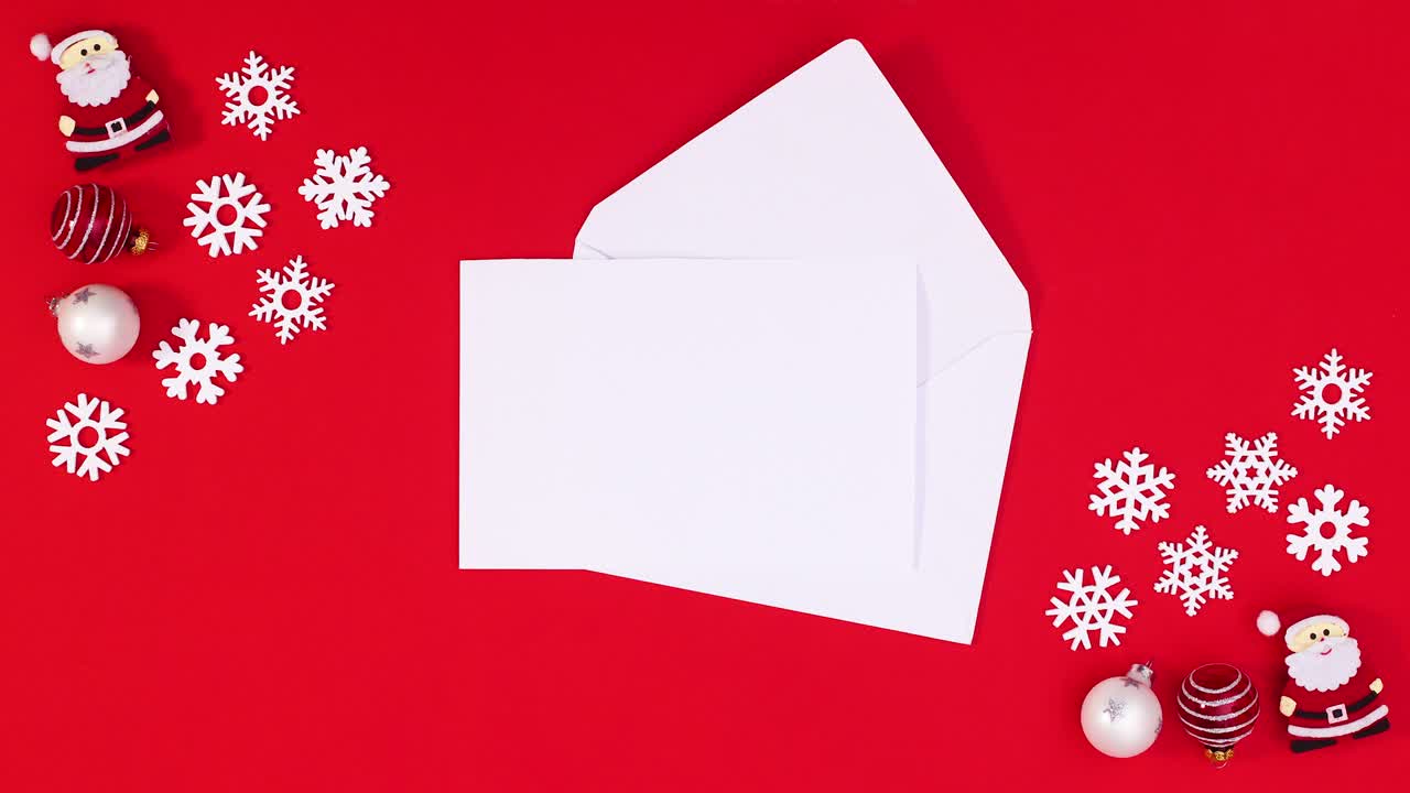 Fiocchi di neve e ornamenti natalizi appaiono e la carta emerge da una busta per testo su tema rosso. Stop motion