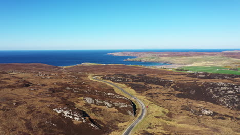 sweeping drone shot over a road in a remote landscape by the sea on a sunny day