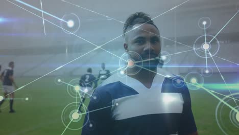 Animation-of-network-of-connections-over-african-american-male-rugby-player-standing-on-sports-field