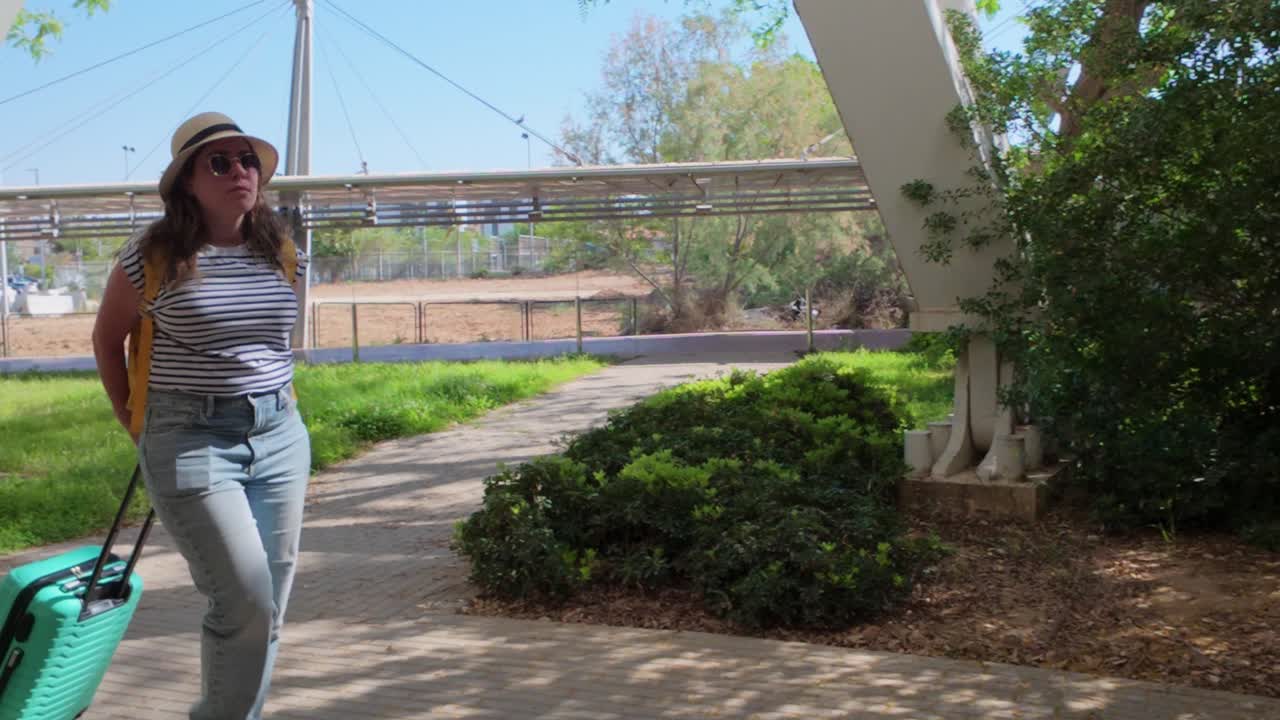 Woman Traveler Walking Through Park with Suitcase