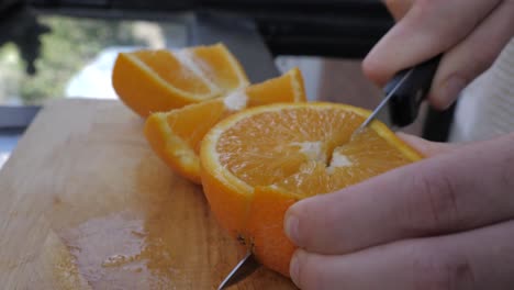 Young male slices in orange in bright Kitchen
