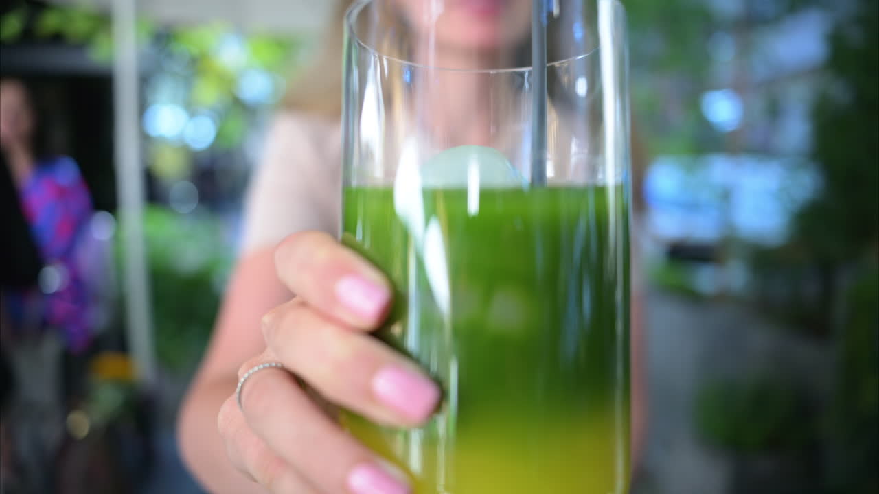 Woman drinking matcha tea with ice at a terrace, slow motion
