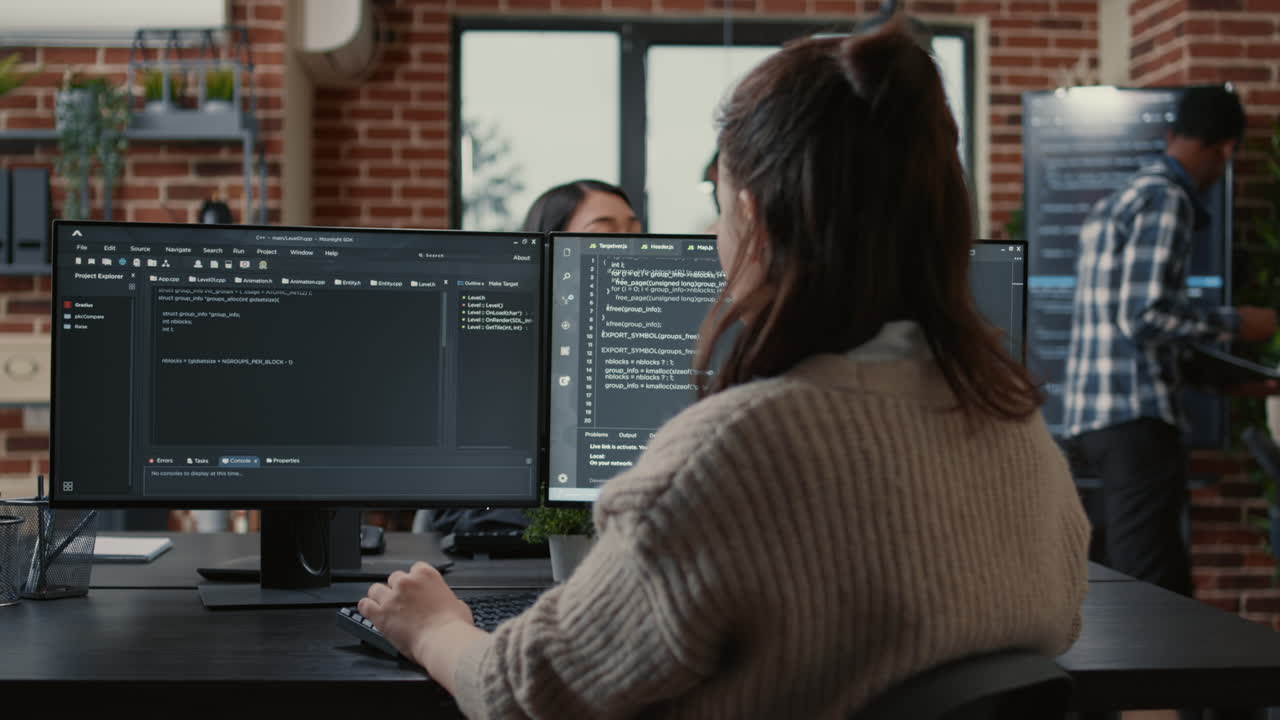 Software programer writing code in front of multiple computer screens