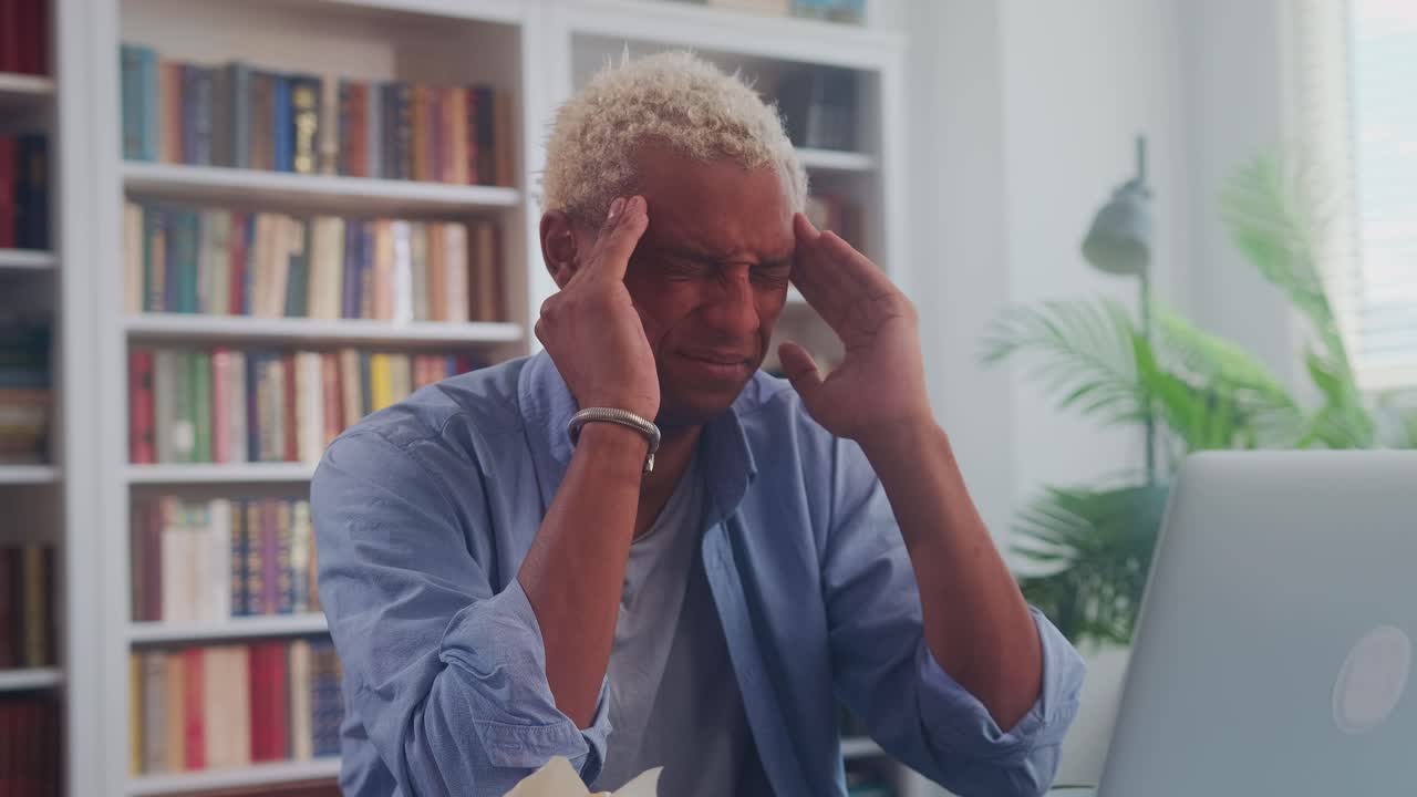 Young tense african american man has headaches due to overwork