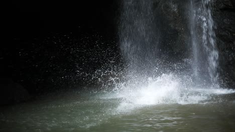 toma en cámara lenta de un hombre haciendo una voltereta frontal desde un acantilado frente a una cascada de leke leke en bali, indonesia, después de una tormenta de lluvia